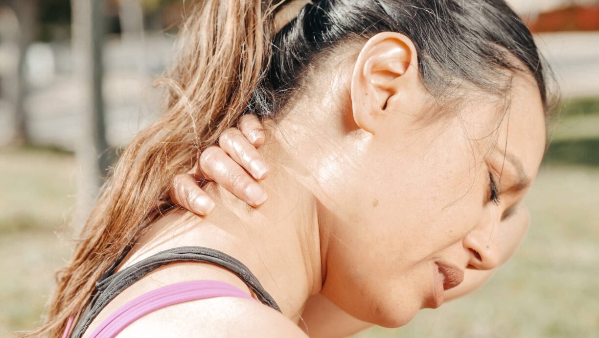 woman holds neck in pain