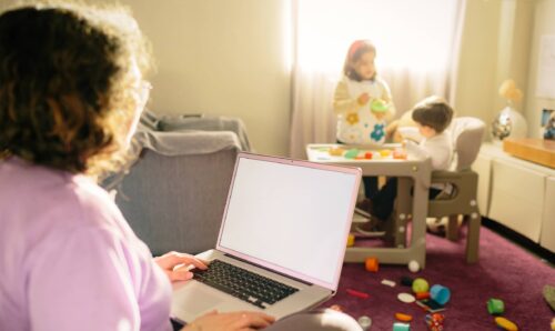 woman working on her laptop while her children play