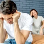 Man and woman sit on bed upset