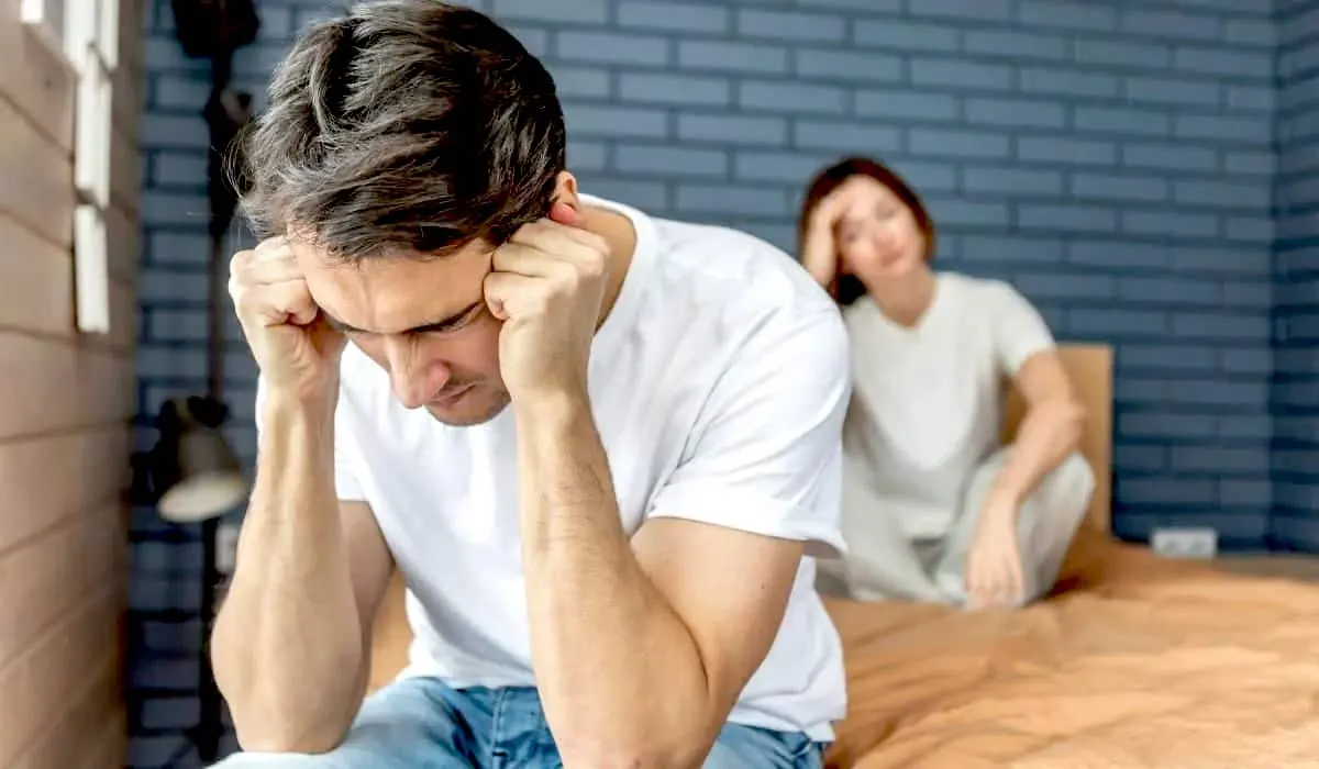 Man and woman sit on bed upset