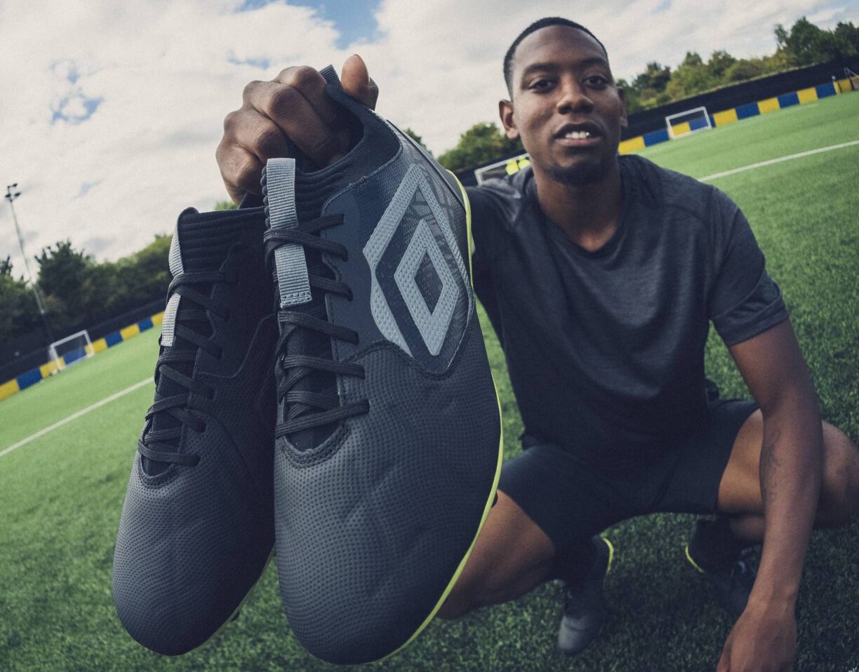 footballer holds up pair of umbro tocco 2 football boots