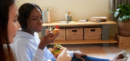 young women eating pizza when resting at home