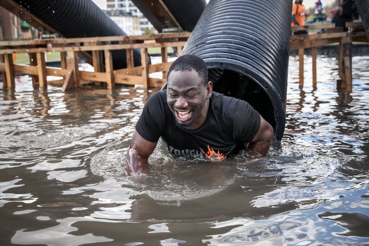 Tough mudder participant exits tube to water