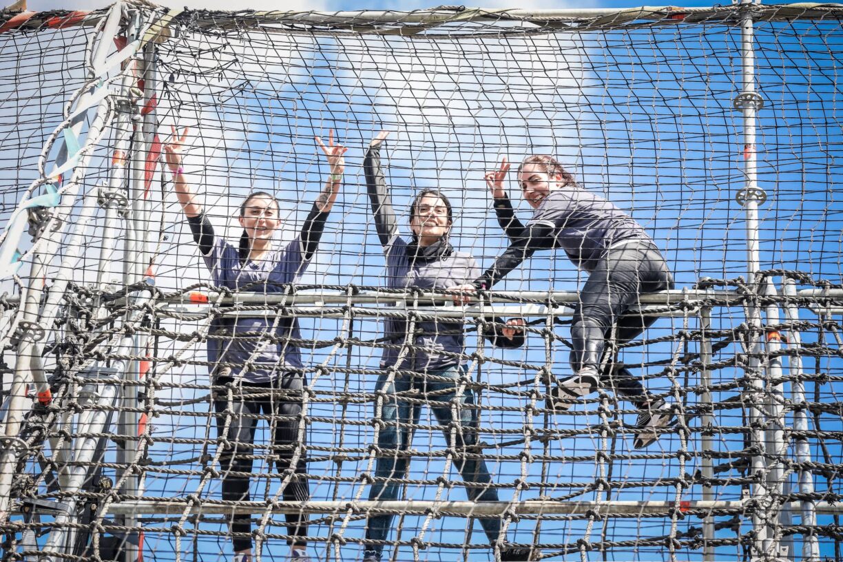 tough mudder participants on net fencing