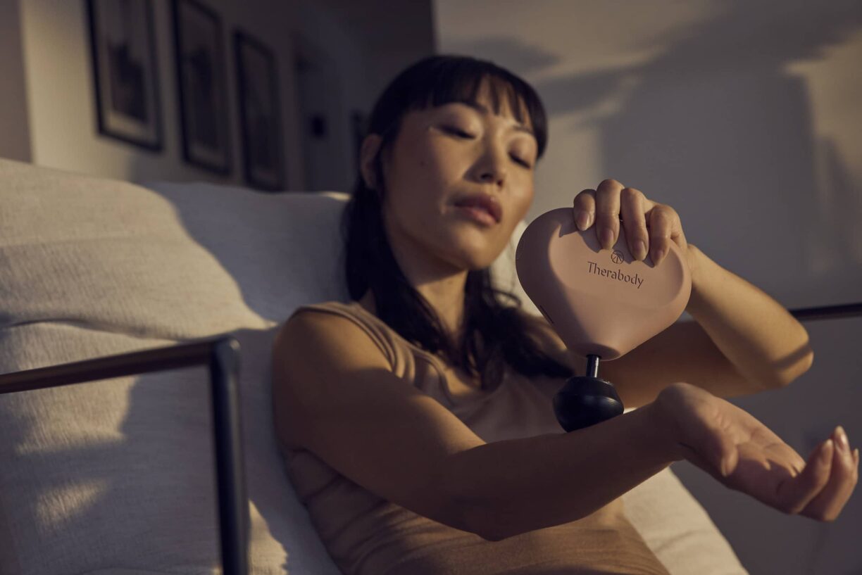 Woman uses therabody mini massager on wrist