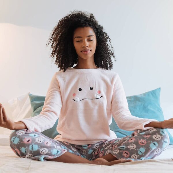 Young black woman relaxed at home doing morning meditation in bed