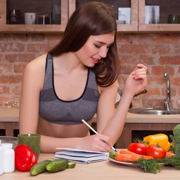 young woman sits at the kitchen table and writes in her diary everything about healthy