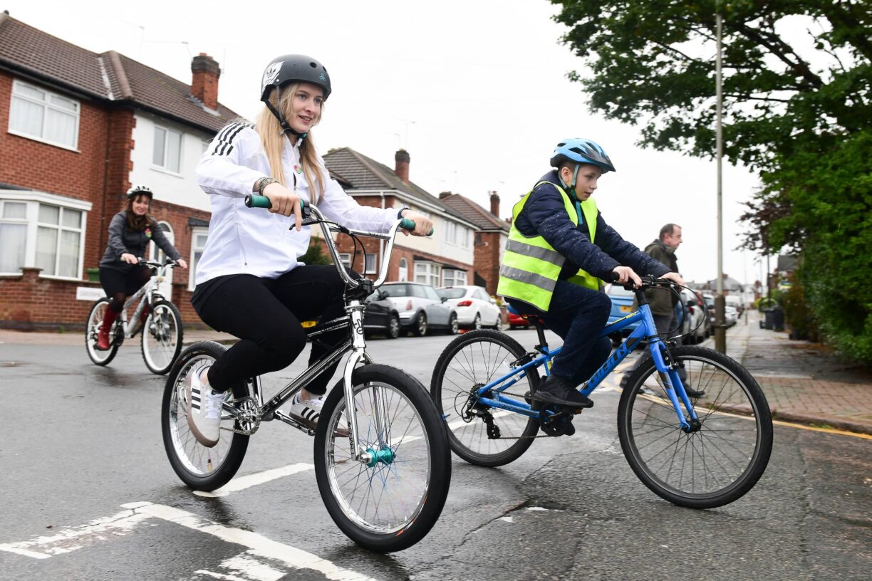 Charlotte worthington rides alongside a youngster on bmx
