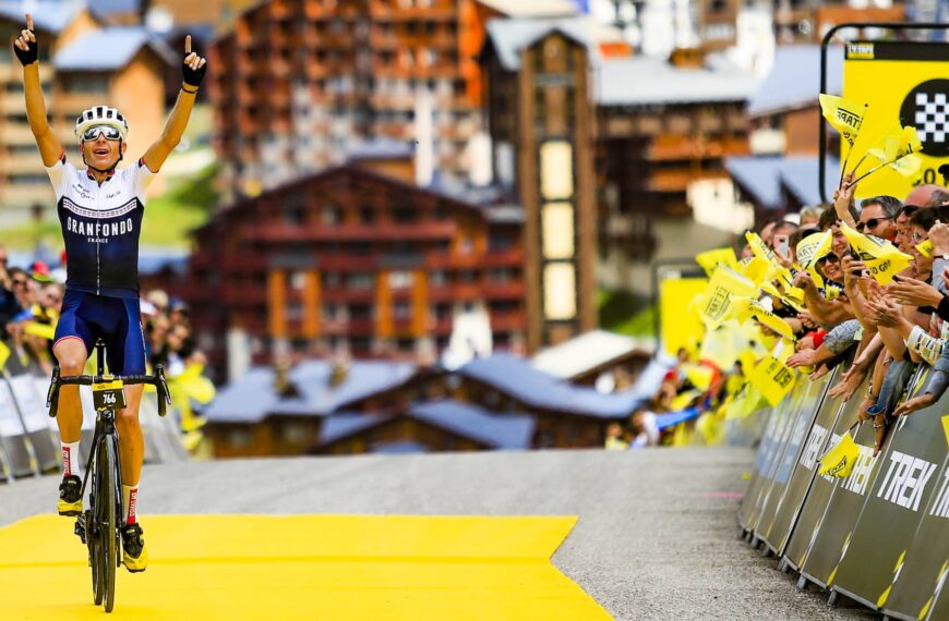 cyclist crosses the line and raises his hands to the sky