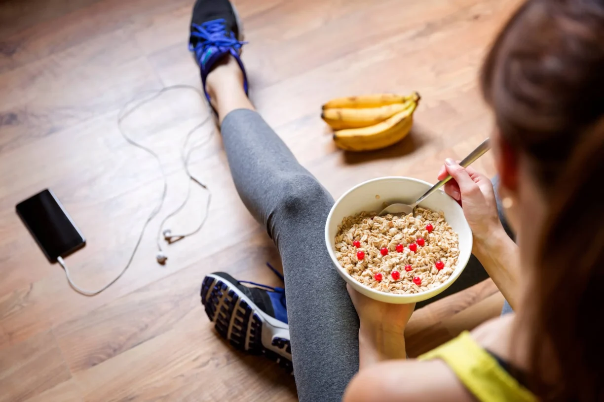 fit woman eating a oatmeal with berries after a workout
