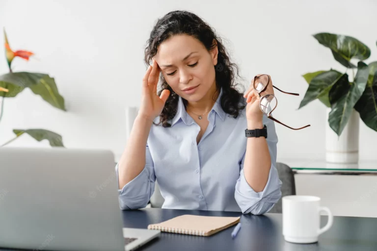woman holds hand to head looking stressed at work