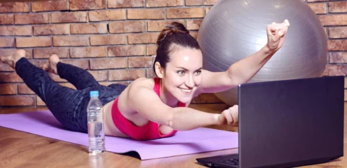 Young smiling woman lying on fitness Mat depicts the flight of a superhero