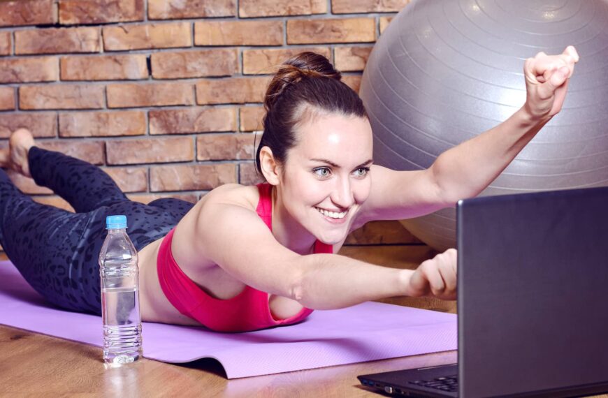Young smiling woman lying on fitness Mat depicts the flight of a superhero