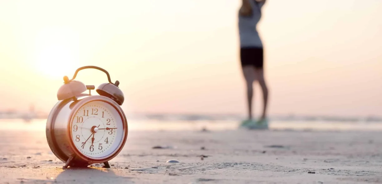 active person on beach with alarm clock in view