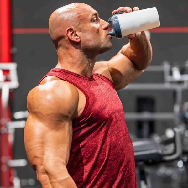 Bodybuilder in t-shirt drinking water with protein and supplements for training at the gym