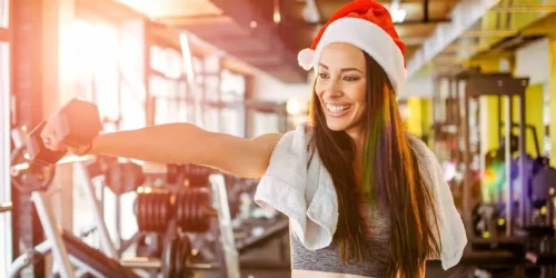 young woman with christmas hat and dumbbells