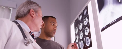 Mid aged medical doctor reviewing x ray of male patient