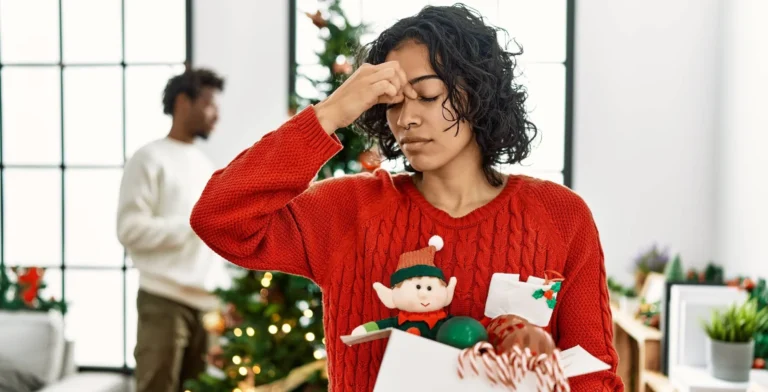 Young woman standing by christmas tree with decorations