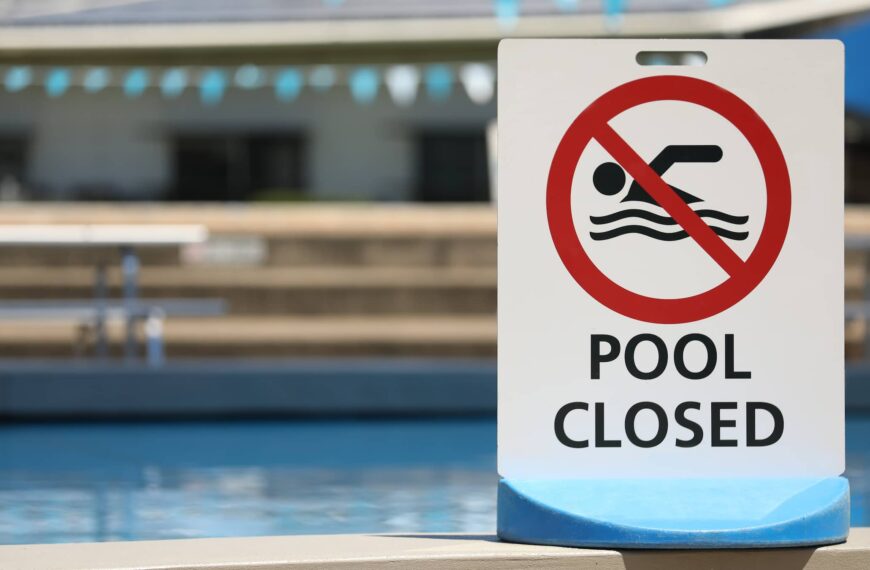 A bright white sign at a local outdoor pool facility saying pool is closed.