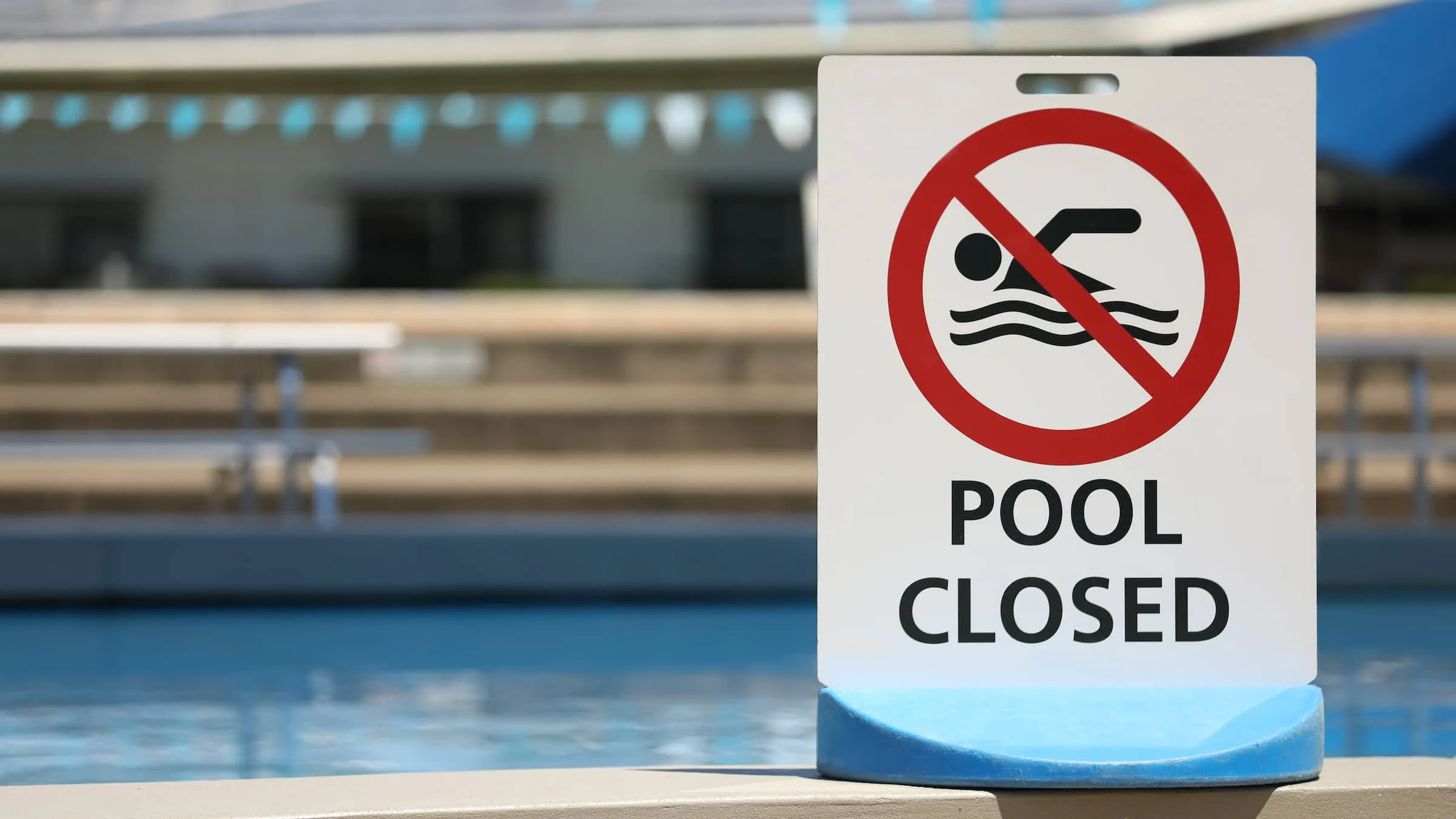 A bright white sign at a local outdoor pool facility saying pool is closed.