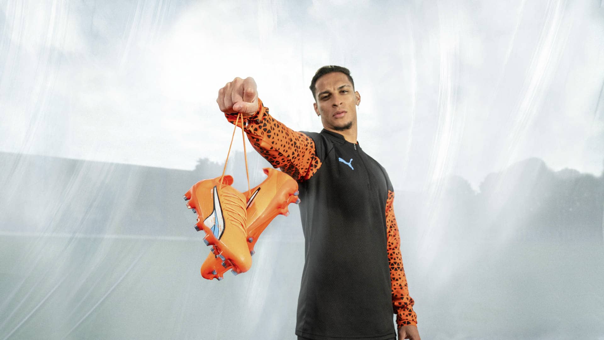 Footballer holds puma ultra supercharge edition in the air by laces