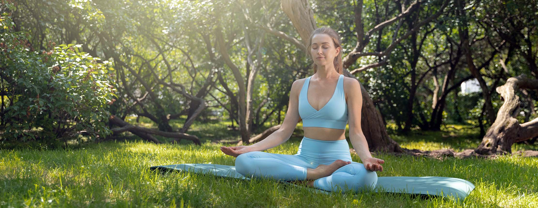 Young woman in stylish eco friendly sportswear practicing yoga in the greenery park.