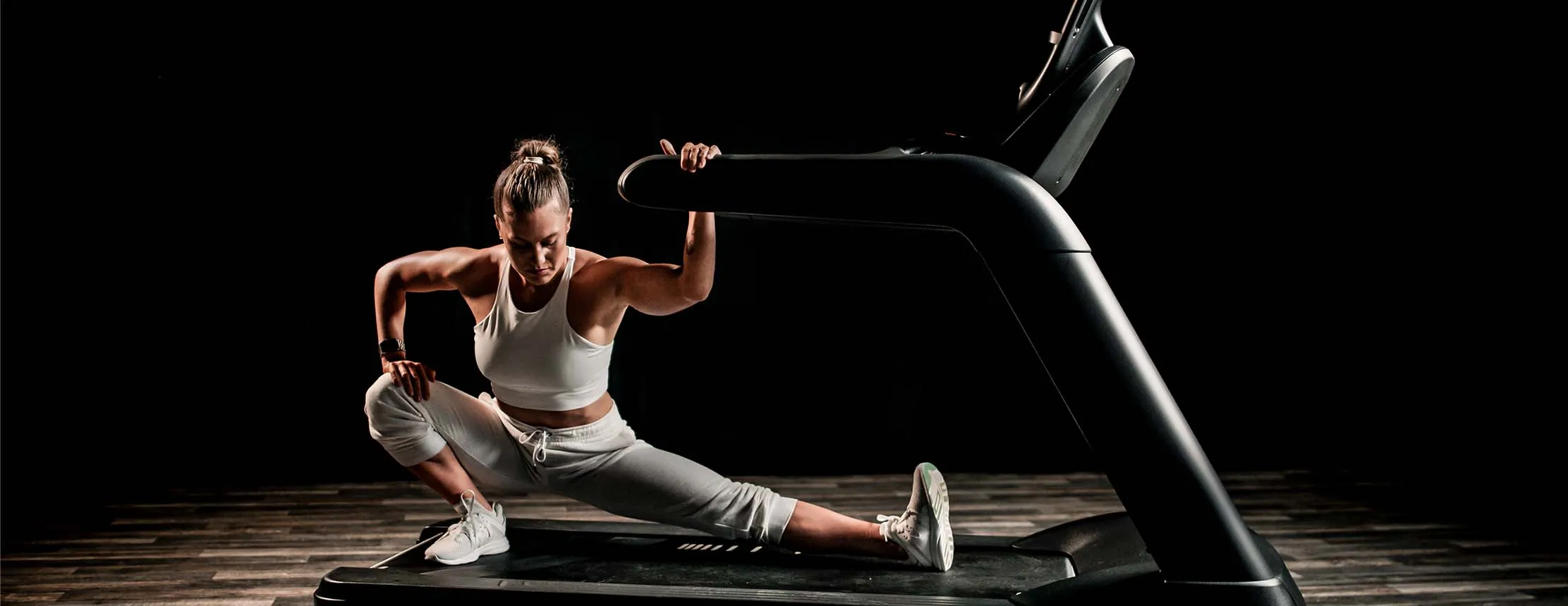 woman performs stretch on treadmill