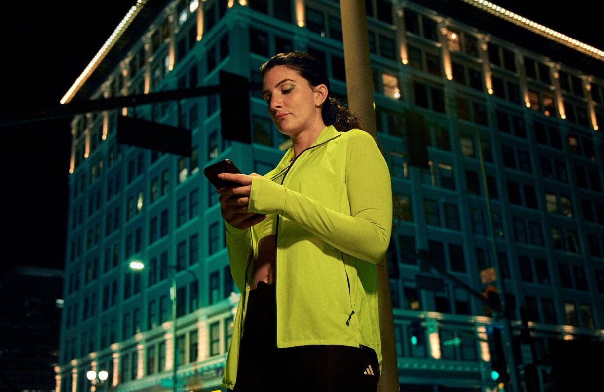 Woman stands checking phone in dark street