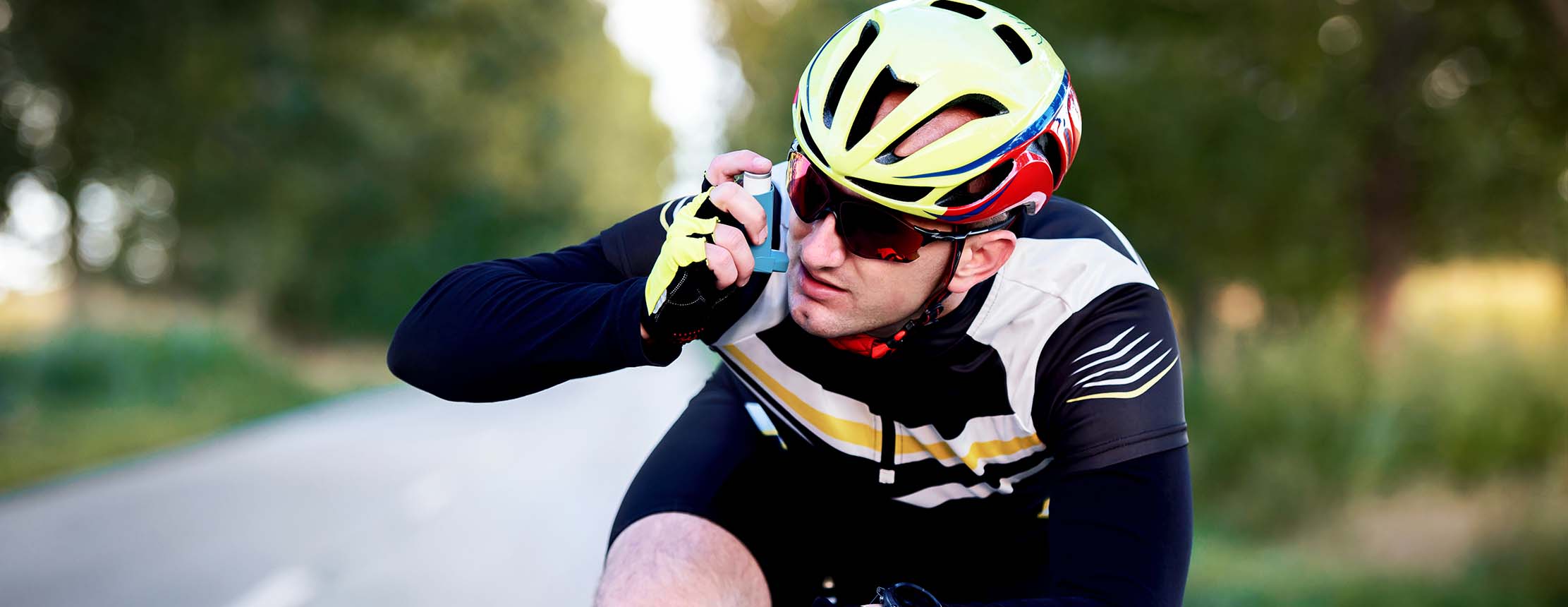 Cyclist using asthma inhaler while riding a bicycle