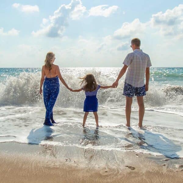 Family hold hands on the beach