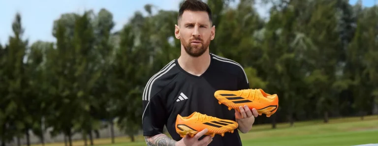 lionel messi holding orange adidas boots