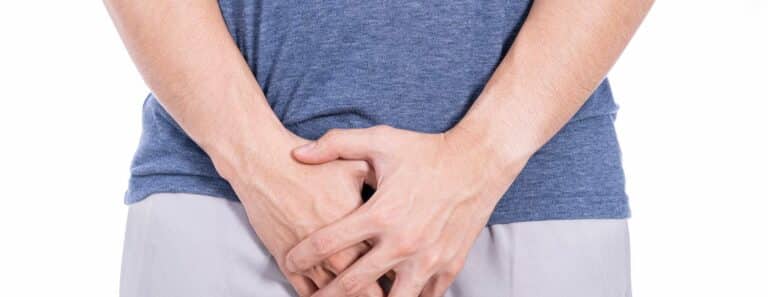 person holds hands over genitals