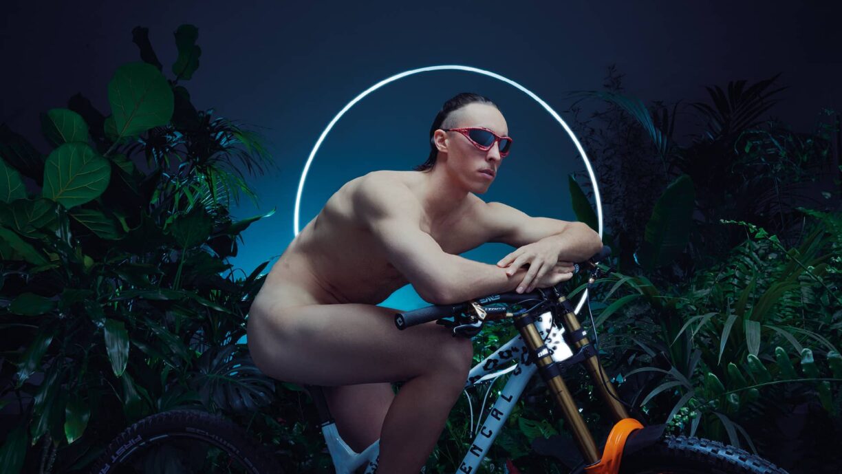 Naked man wearing oakley sunglasses sits on bike