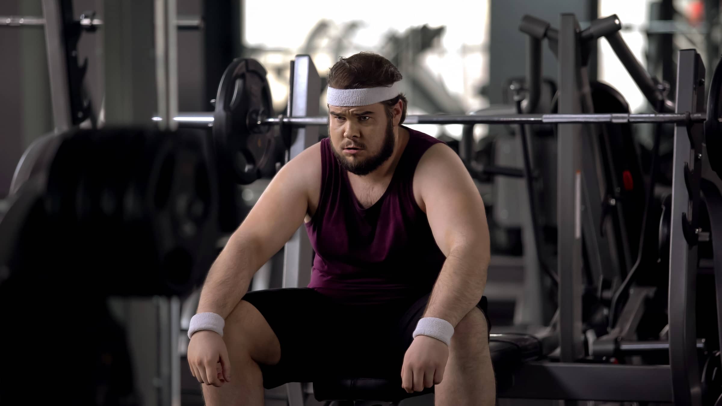 Tired man thinking over problems, desire to lose weight, gym workout