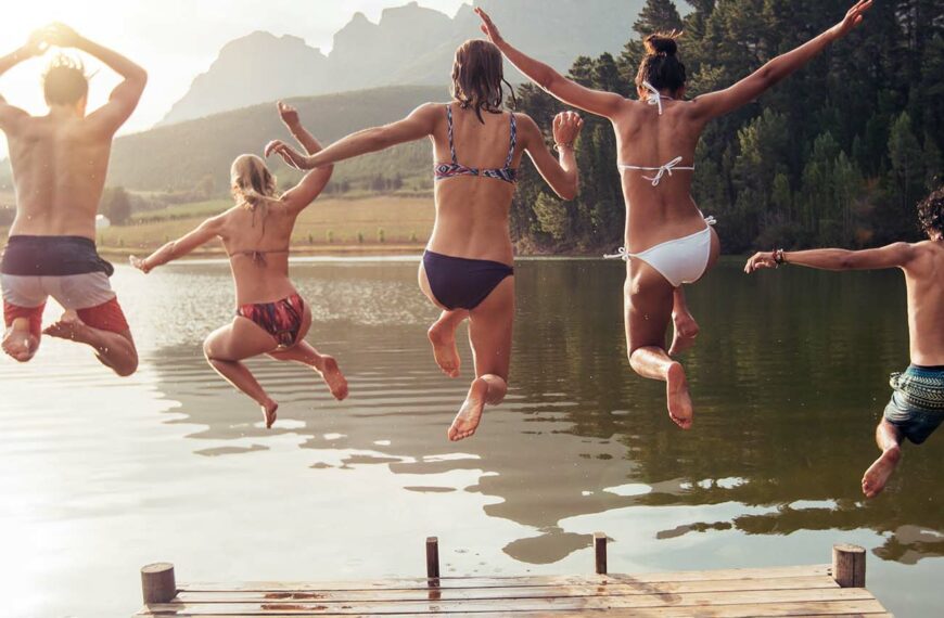 Young friends jumping into lake from a jetty