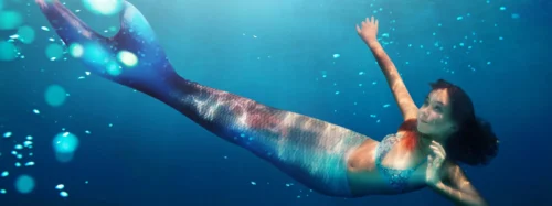 Portrait of a girl mermaid with tail swim under water in the ocean