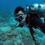 person scuba diving at bottom of the ocean