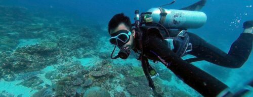 person scuba diving at bottom of the ocean