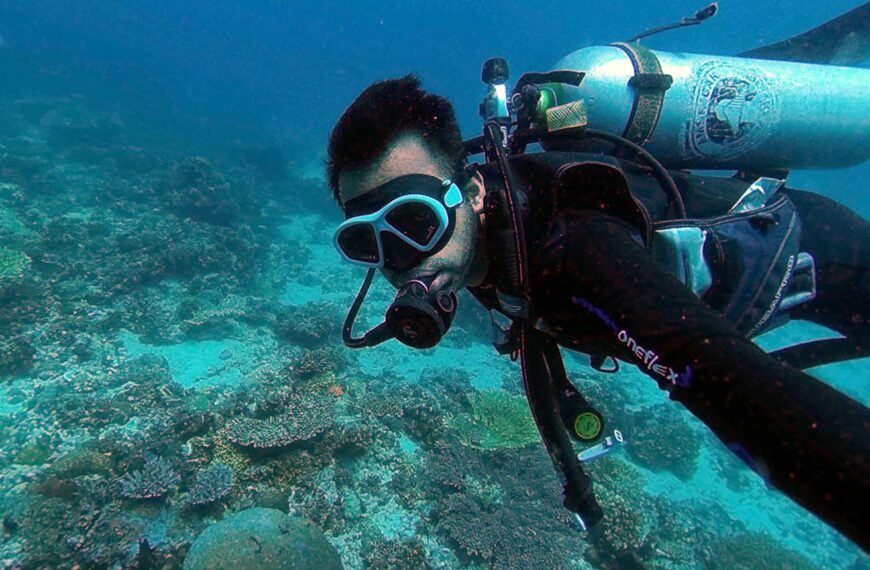 person scuba diving at bottom of the ocean