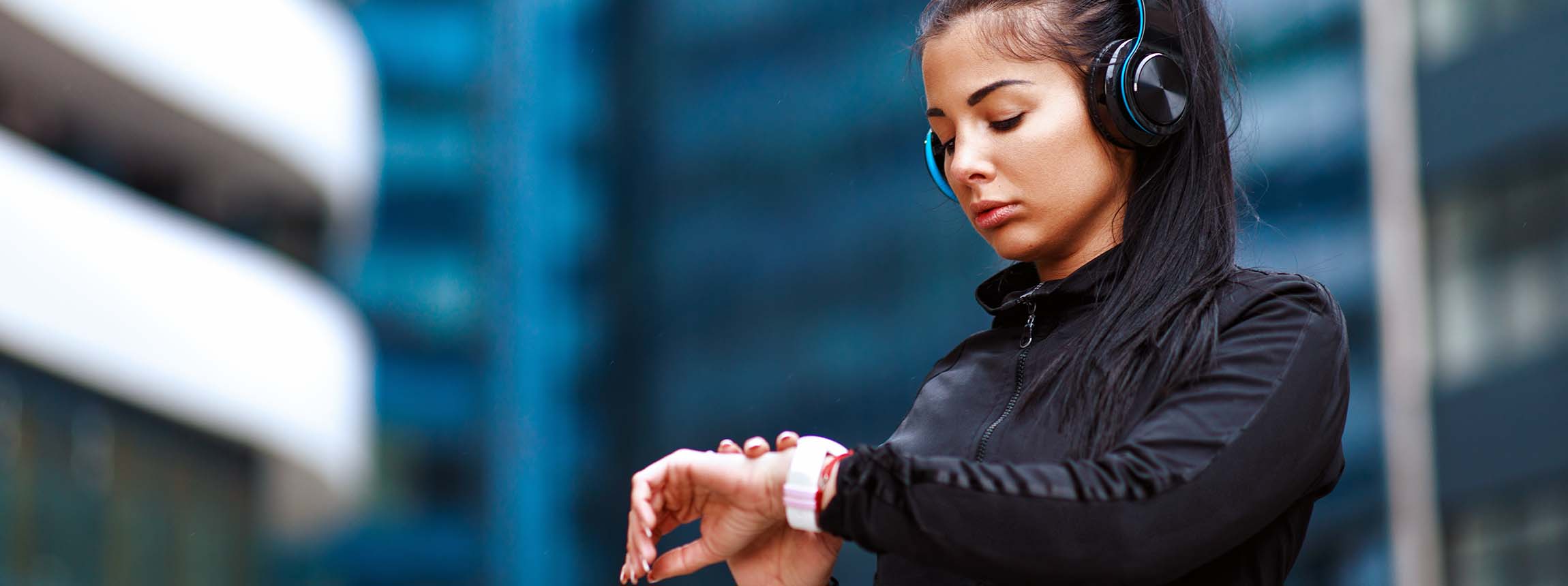 Young woman checking time at smartwatch after jogging in the city