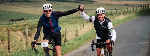 two male cyclist hold hands in celebration