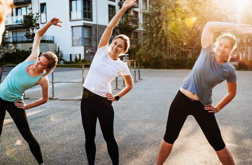 women perform stretches with sunrise in background
