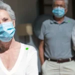 mature people stand wearing facemasks