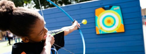 young person takes aim with bow and arrow