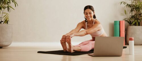 Woman doing yoga at home watching video on laptop