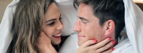 couple under bed sheets embrace