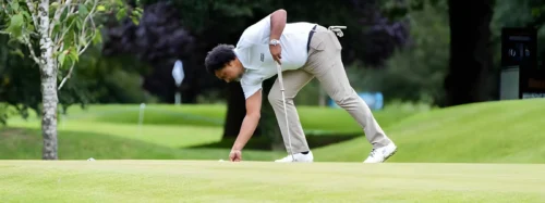golfer picks up ball on green