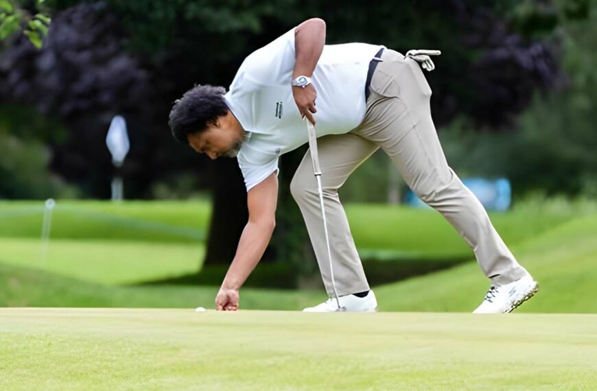 golfer picks up ball on green