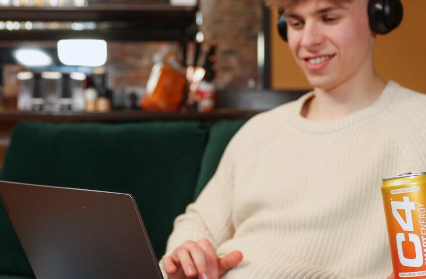 young person at laptop with can of c4 energy drink in hand