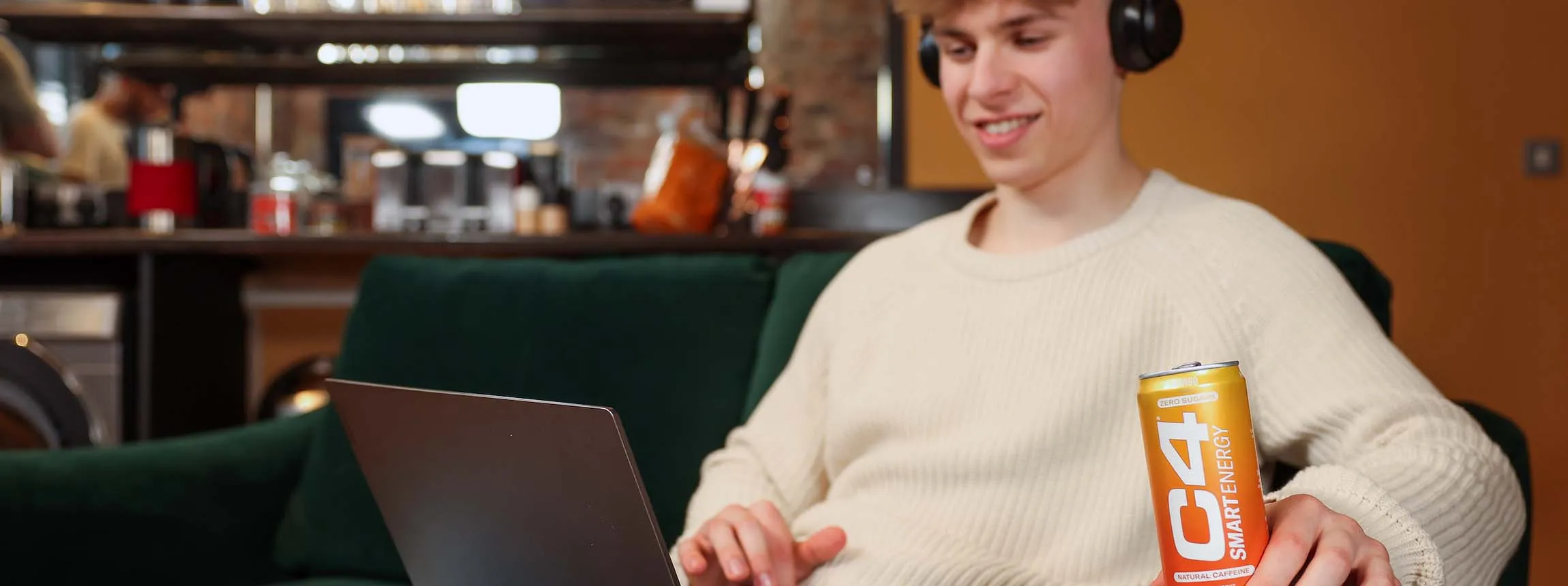 young person at laptop with can of c4 energy drink in hand
